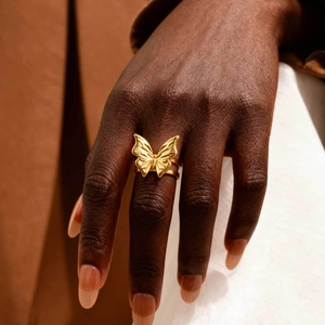 Detailed close-up of golden butterfly ring with double-layered band on model hand