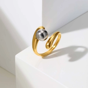 Detail of minimalist gold-plated open ring featuring a contrasting silver spherical bead