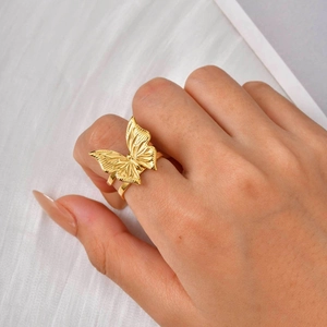 Macro detail of golden 3D butterfly ring with intricate wing textures and polished finish