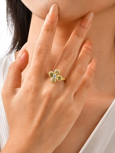 Primer plano de un anillo floral dorado con pétalos texturizados y circonita central