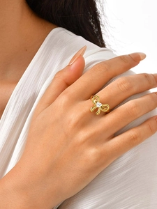 Primer plano de un anillo de lazo dorado con circón de corazón en el dedo