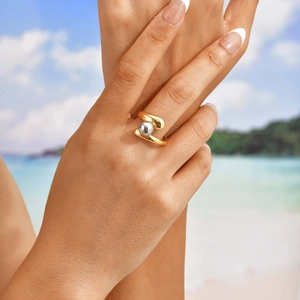Detail of minimalist open gold ring with silver bead accent on a model's hand