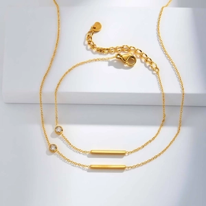 Détail d'une chaîne dorée avec barres rectangulaires, zircon et fermoir mousqueton