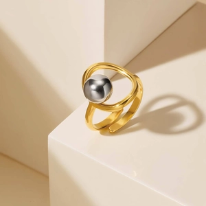 Detail of minimalist gold wavy ring featuring a large silver sphere on cream props