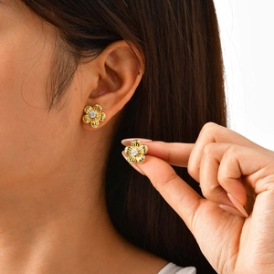 Detalle de pendientes de flores doradas con circón brillante usados por una modelo