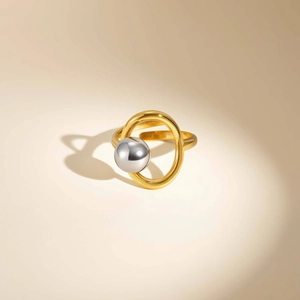 Close-up of gold geometric ring featuring a silver sphere with a polished mirror finish