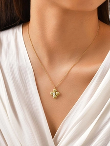 Detalle del collar de trébol dorado con circón y diseño radial en una modelo