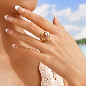 Modern gold irregular open ring with silver bead accent worn by model against blue sky
