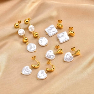 Detailed shot of 18k gold plated pearl earrings on silk background with heart shapes