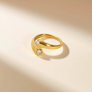 Macro detail of gold-plated open ring featuring two sparkling heart-shaped zircon stones