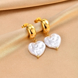 Close-up of golden stainless steel hoop earrings with white heart pearl pendants