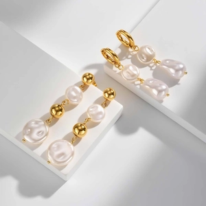 Detail of elegant gold-plated earrings with white pearls on a minimalist display