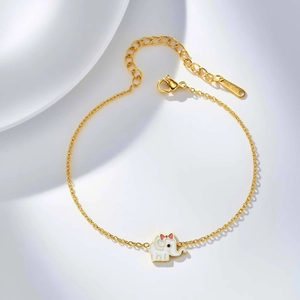 Detalle de pulsera dorada con colgante de elefante en esmalte blanco y lazo rosa suave