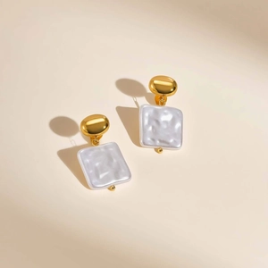 Detailed macro shot of gold oval earrings with white FF embossed pendants and French style