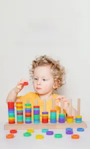 Close-up of a child playing with a Montessori rainbow ring stacker for counting and sorting