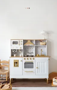 Macro detail of wooden play kitchen featuring white cabinets with golden hardware accents
