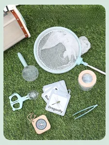 Kids outdoor exploration set with net, wooden compass, and magnifying glass on grass