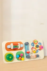 Dettaglio della tavola busy board in legno con ingranaggi colorati e moduli sensoriali