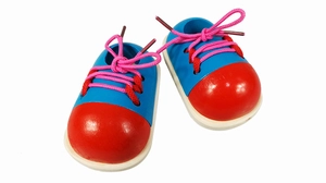 Detail of wooden shoe tying toy with blue body red toe and pink laces for kids