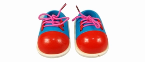 Detail of wooden shoe toy featuring blue body, red toe, and pink laces for tying practice