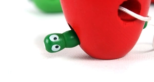 Macro view of wooden apple lacing toy showing smooth red paint and white threading cord