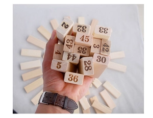 Gros plan d'une main tenant des blocs en bois naturel numérotés pour jeu d'empilage