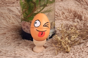 Macro detail of wooden toy egg with funny face expression on a solid wood egg holder stand