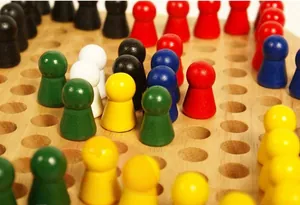 Nahaufnahme eines hölzernen Halma-Bretts mit bunten Spielfiguren und runden Aussparungen