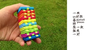 Detailed view of the colorful Jacob's Ladder wooden toy held by a hand on a grass background