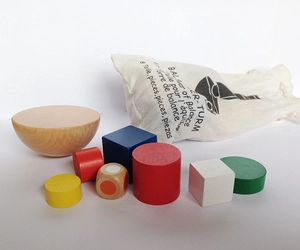 Détail du jeu d'équilibre en bois avec cylindres colorés, dé et sac de rangement inclus