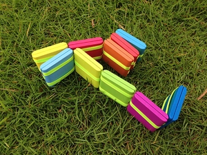 Detail of colorful wooden flip tiles with fluorescent stripes on green grass background