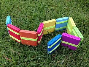 Close-up of colorful wooden blocks with green elastic bands on a natural grass background