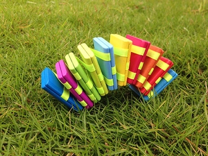 Detailed view of colorful wooden Jacob's ladder toy with silk ribbons on green grass