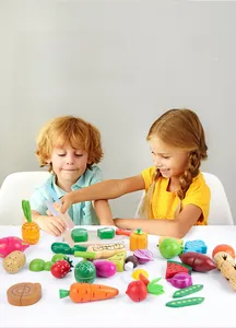 Kids playing with wooden magnetic vegetable and fruit cutting toys on white table