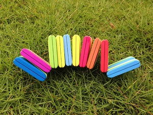 Outdoor close-up of 10 colorful wooden flip boards arranged on green grass for play