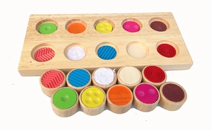 Detail of wooden sensory board showing 10 textured cylinders for tactile learning
