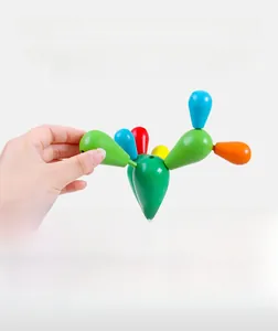 Close-up of a hand assembling colorful wooden cactus blocks on a natural base