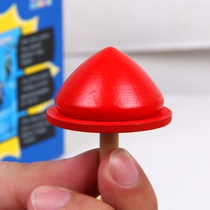 Toupie en bois rouge en forme de champignon, tenue en main avec une finition lisse polie