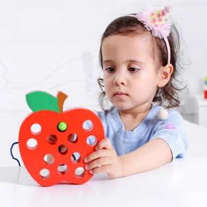 Close-up of a child using the wooden apple lacing toy for fine motor skill training