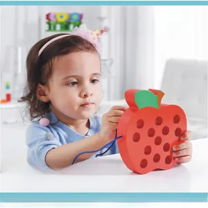 Close-up of a child playing with a red wooden apple lacing toy for fine motor skills development