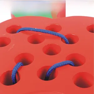 Detail of blue thread passing through holes on red apple-shaped wooden toddler toy