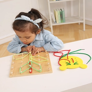 Detail of child using wooden geoboard with rubber bands and bear lacing toy