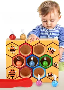 Detail of wooden beehive toy with colorful bees and red tweezers for fine motor skills