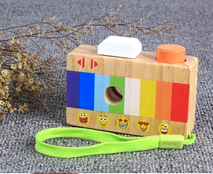 Detail of wooden toy camera with rainbow stripes, emoji stickers and green strap