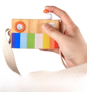 Detail of wooden toy camera with rainbow stripes and a white woven neck strap