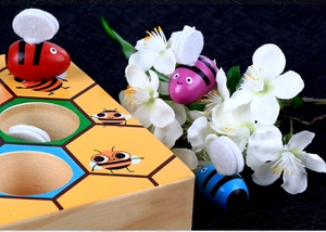 Detail of colorful wooden bees and felt wings on a Montessori hive board game