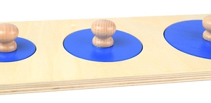 Detail of wooden Montessori puzzle featuring three blue circles with spherical knobs