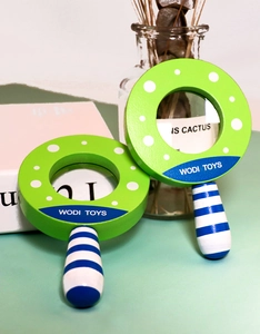 Close-up of wooden magnifying glass toy with green polka dots and striped blue handle