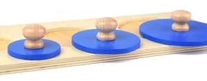 Macro detail of Montessori wooden knobbed cylinders with blue circular inserts for toddlers