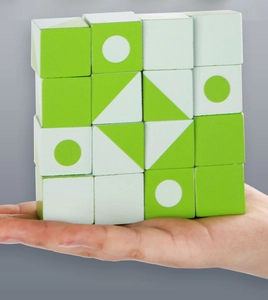 Close-up of child holding 16 wooden logic blocks with green and white geometric patterns